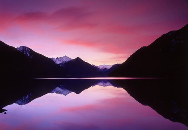 Serene lake under a purple setting sun with mountains in the background